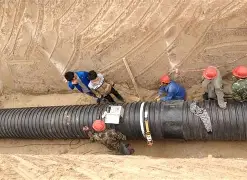 Workers installing HDPE double-wall corrugated pipe in sewage drainage project